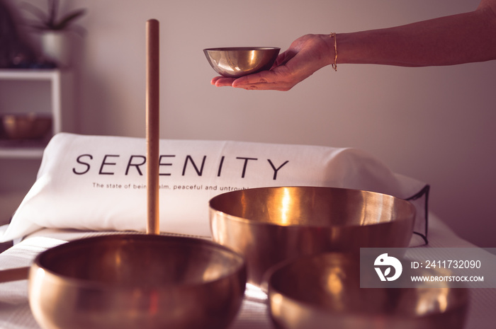 Sound healing and serenity concept. Female therapist holding singing bowl over massage table.