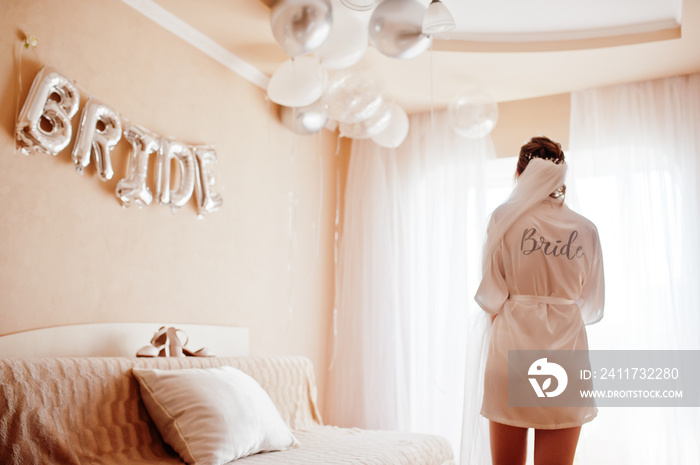 Wedding day preparation. Bride wearing a white bridal bathrobe.