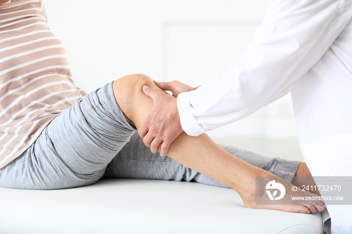 Doctor examining mature woman with joint pain in clinic