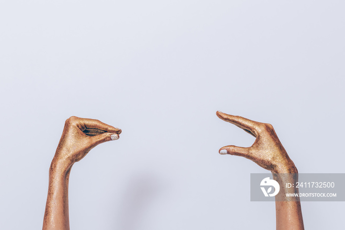 Women’s hands covered with gold paint depict two people talking