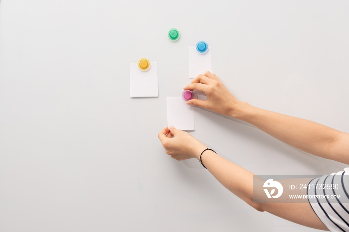 Image of white board and hand attaching pieces of paper to the magnetic board.