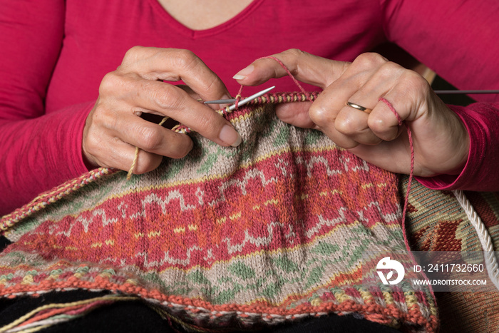 Close up of hands knitting a Fair Isle pattern hat.