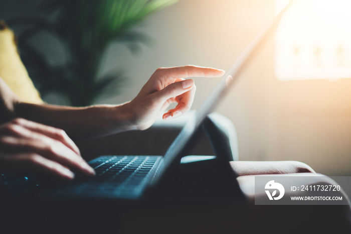 Female freelancer businesswoman working from home via modern portable computer device, young hipster girl using digital tablet while working at loft studio, flare light on the background