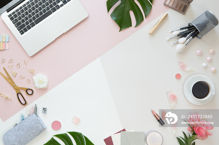 Pastel office table desk with computer laptop, green palm leaves, flowers, clipboard and beauty accessories, top view and flat lay. Home fashion women office workspace isolated on pink background.