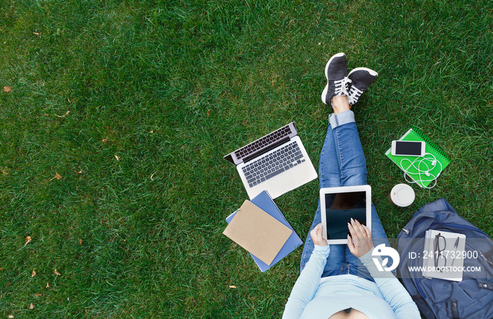 Top view of woman with laptop sitting on the green grass