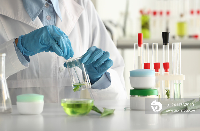 Woman making organic cosmetics with aloe in laboratory