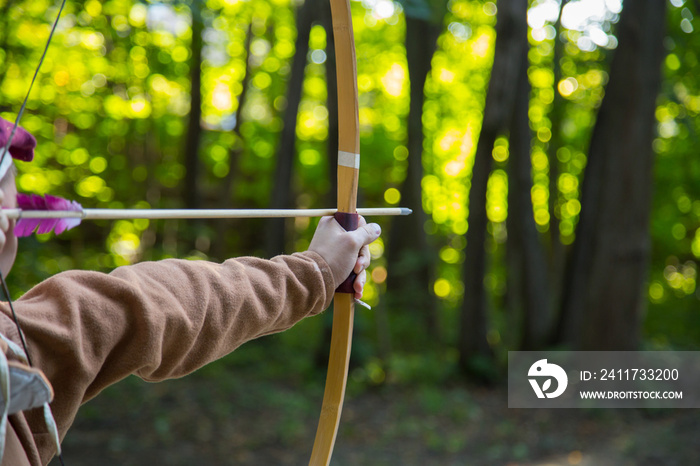 Medieval male archer shooting targets with wooden bow at historical festival - close up shot. Archery and medieval culture concept