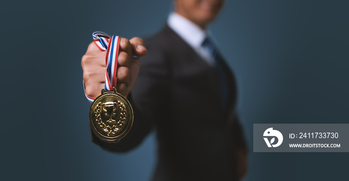 A business man holding a gold medal. Achieving success in business and achieving business goals.