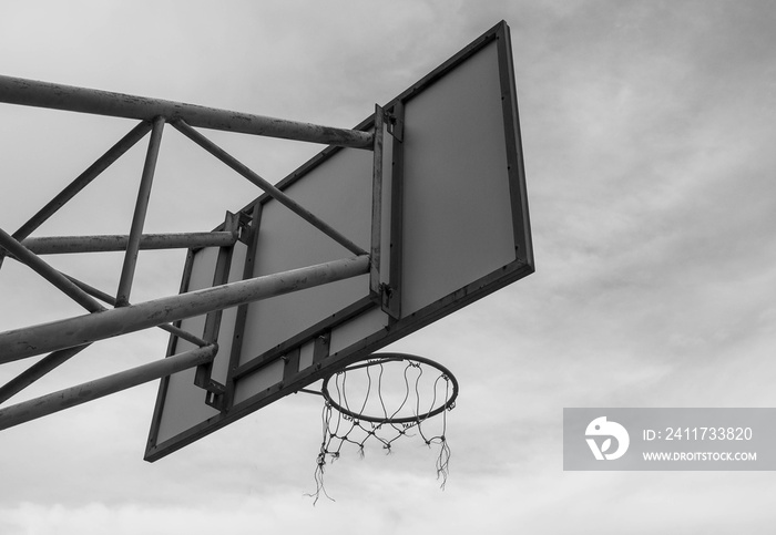 The back image of the basketball board hoop with the loop on the sky background. Black and white style tone.