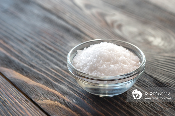 Bowl of salt on the wooden background