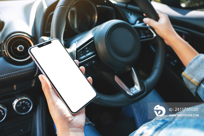 Mockup image of a woman holding and using mobile phone with blank screen while driving car