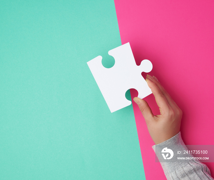 female hand holds a big empty white puzzle over a colorful background