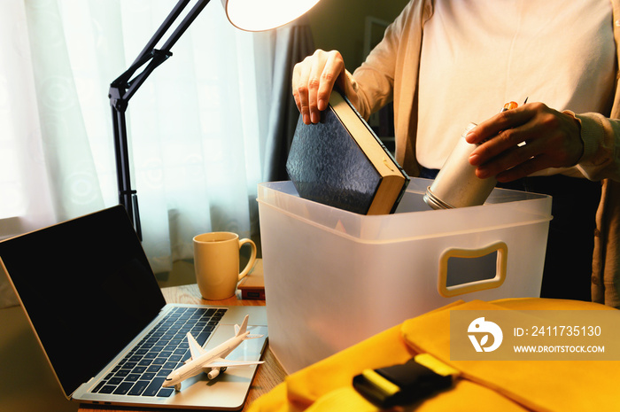 Female student abroad keep the book in plastic box and backpack with laptop on desk at home to prepare for the journey to go back to study at university.