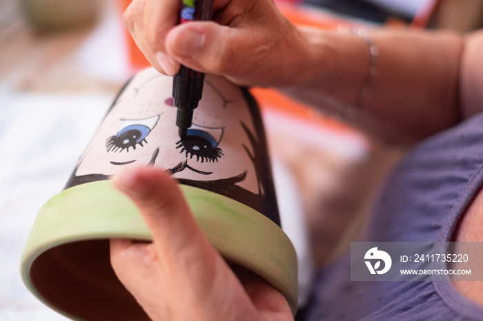 Art, creativity and people concept - close up of female artist drawing and painting a flower pot