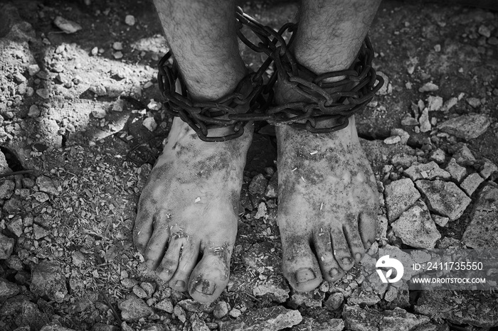 Close-up shot of barefoot legs tied up with old chain