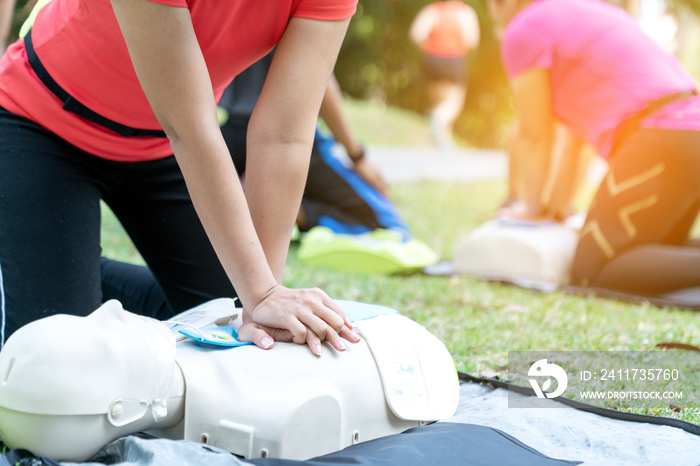 Asian female or runner woman training CPR demonstrating class in park by put hands and interlock finger over CPR doll give chest compression. First aid training for heart attack people or lifesaver.