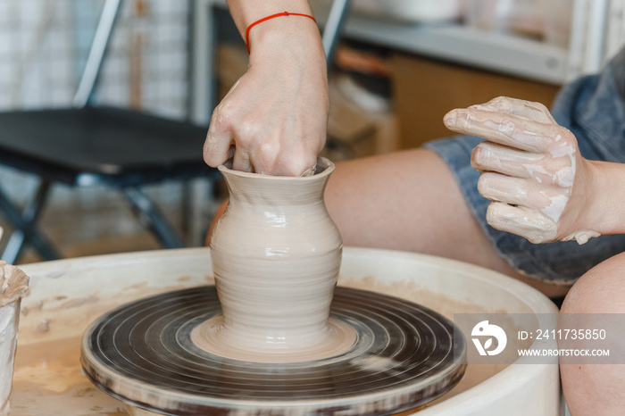 Close-up of female hands sculpting clay on a Potter’s wheel. Concept of hobby and cretivity at home and in the Studio workshop