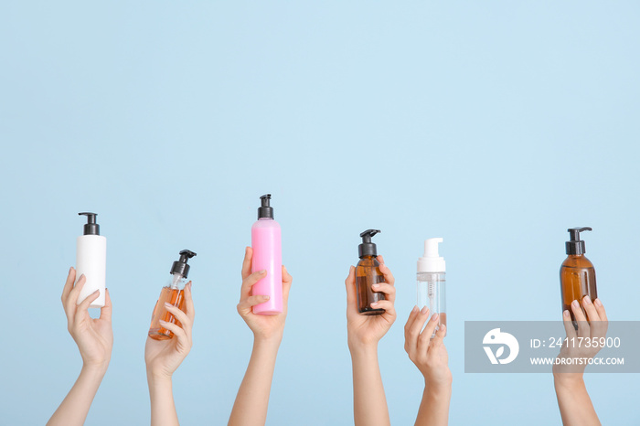 Female hands with different cosmetic products in bottles on color background