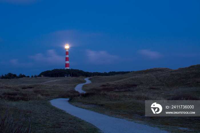 Path leading through the dunes to the lighthouse of Ameland at night