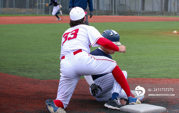 Baseball player sliding into third base whth the third baseman applying the tag