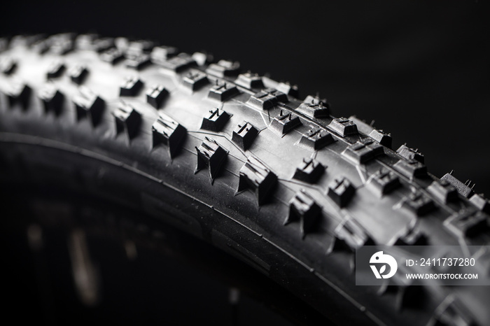 Modern MTB race mountain bike tyre isolated on black background in a studio