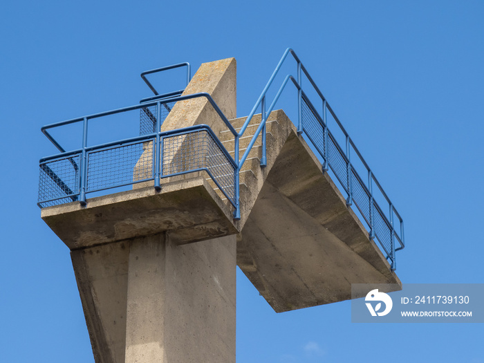 closeup of stairs and railing leading to a high dive board at a swimming pool