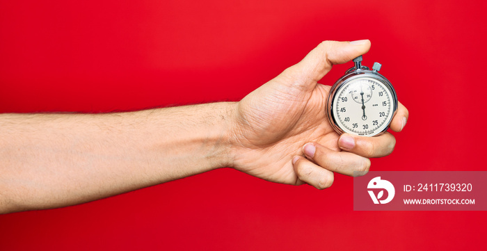 Beautiful hand of man holding stopwatch doing countdown over isolated red background