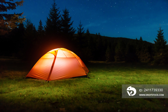 Illuminated tent in night forest