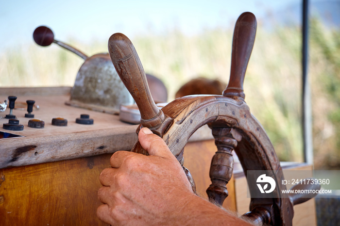 Closeup man hand holding a sailing vessel wheel.