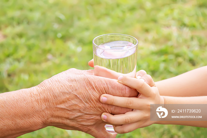 Grandmother giving a glass of clean water to a child. Selective focus.