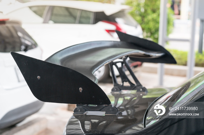 car part ; Close up detail of a custom racing carbon fiber spoiler on the rear of a modern car with copy space