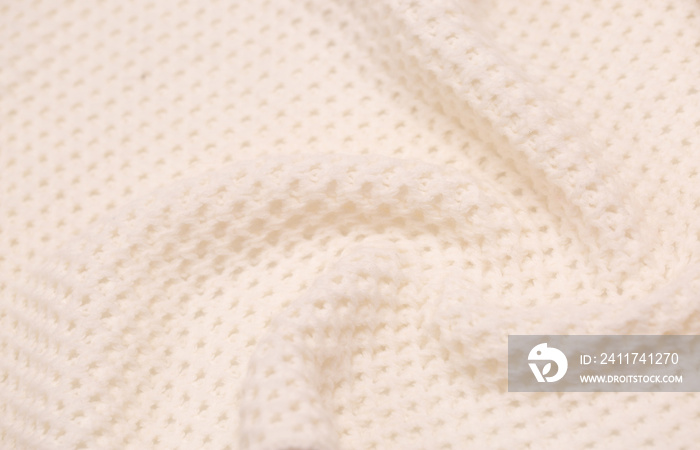 Knitted surface of woolen things as a background. Close-up of soft white texture of knitted patterns. Warm winter clothes. Background textile surface with copy space for text.