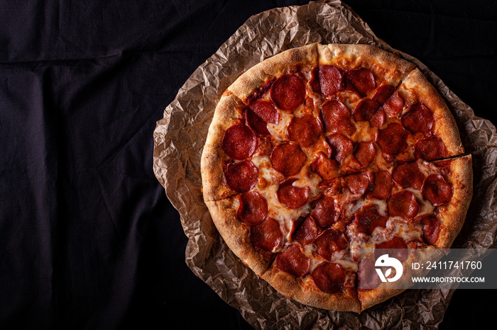 pizza peperoni on black stone background