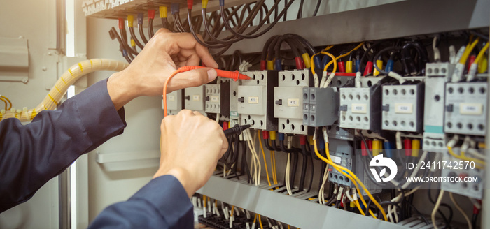 Electrical engineer using measuring equipment to checking electric current voltage at circuit breaker and cable wiring system , Electrical service concept .