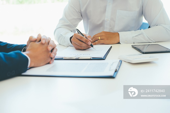 Business young man in shirt insurance agent showed the contract and pointing it while sitting together with man at the desk in office