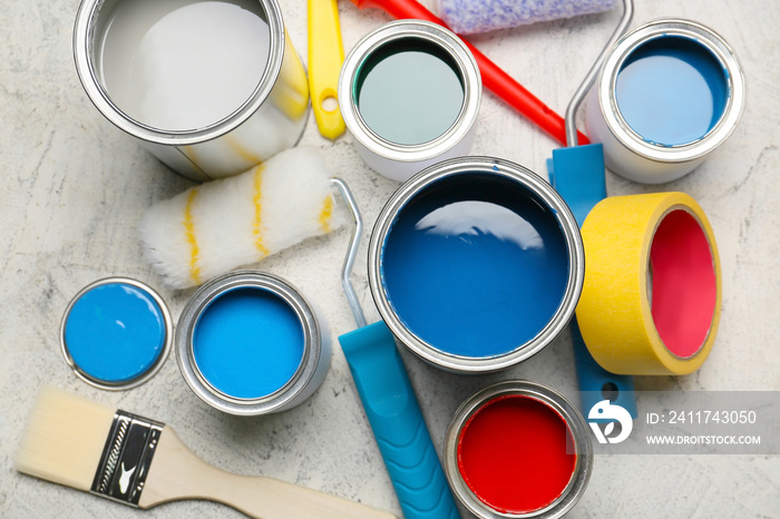 Cans of paints and tools on light background