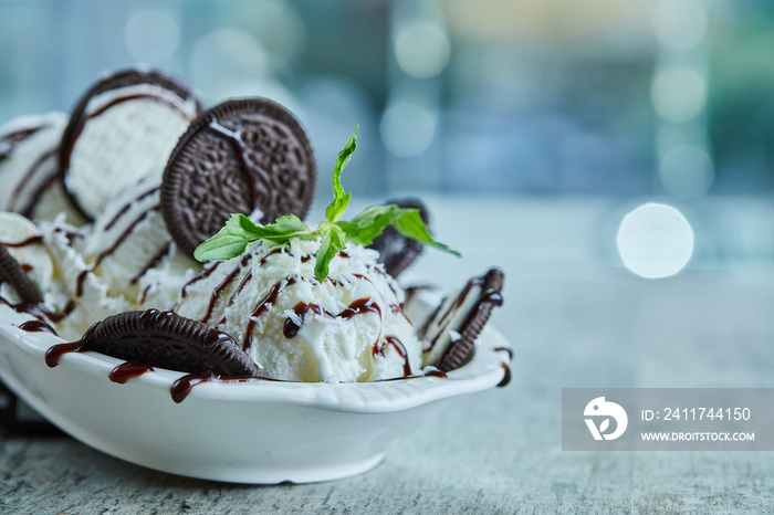 Oreo ice-cream with chocolate syrup and mint in the white plate on the marble background