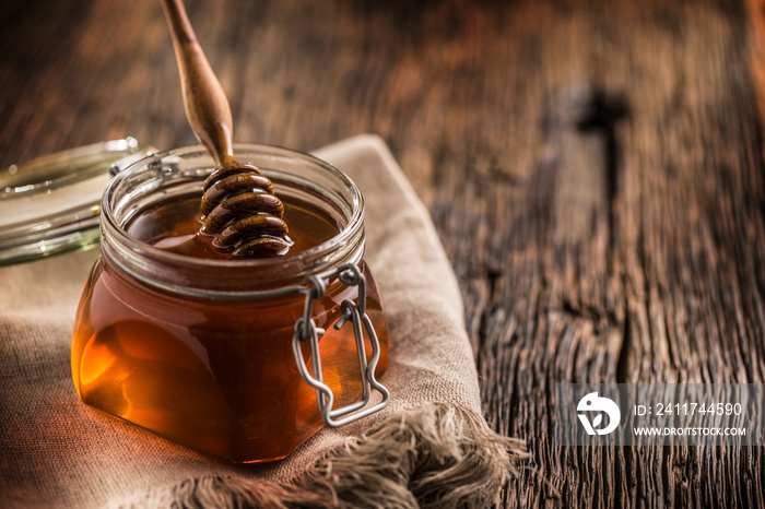 Honey jar with dipper on old woodn table