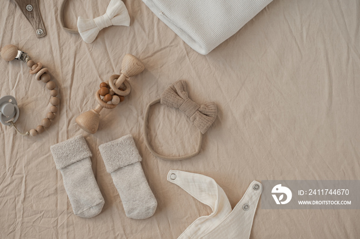 Flatlay aesthetic Scandinavian newborn baby clothes, accessories, toys collage on neutral pastel peach linens. Trendy elegant neutral pastel colour infant stuff. Top view