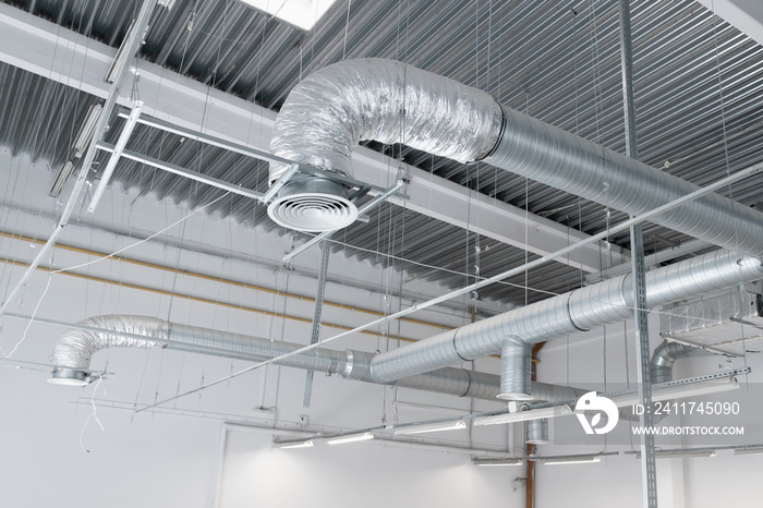 Ventilation and air conditioning system on the ceiling of an industrial building, metal ventilation pipes