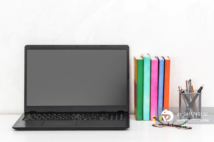 Laptop with blank screen and books on the desk.