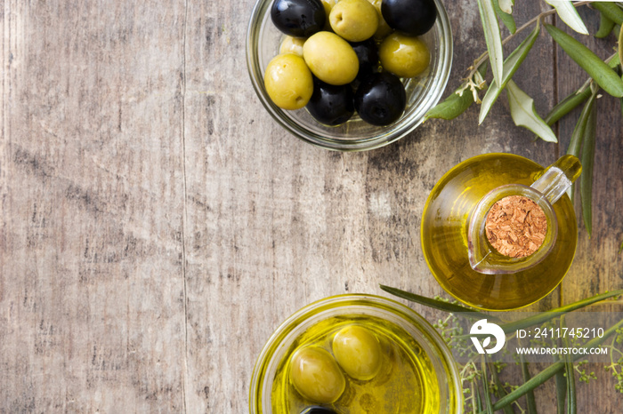 Virgin olive oil in a crystal bottle on wooden background. Top view