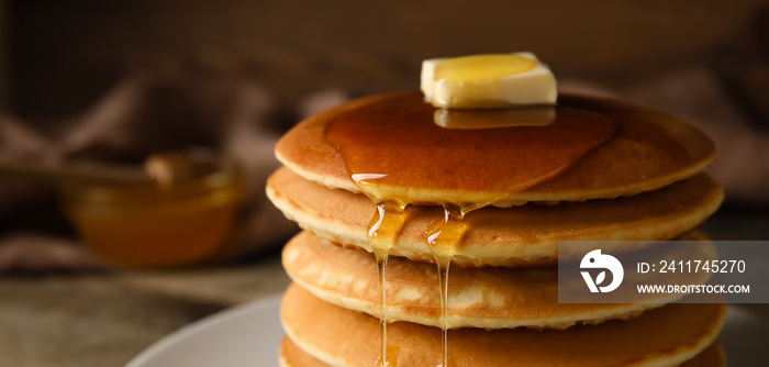 Tasty pancakes with honey and butter on table, closeup