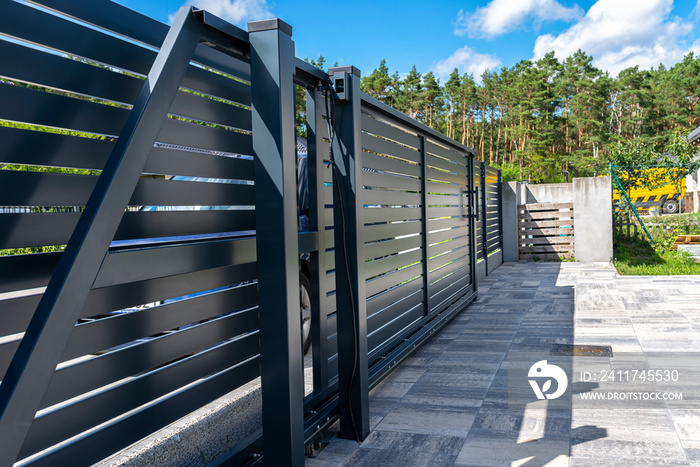 Modern panel fencing in anthracite color, visible sliding gate to the garage as well as a handle and a lock.