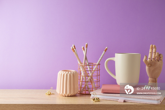 Stylish feminine table with coffee cup, notebook and pencils over purple background. Back to school concept