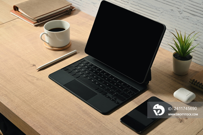 Digital tablet with wireless keyboard, smartphone and cup of coffee on wooden table