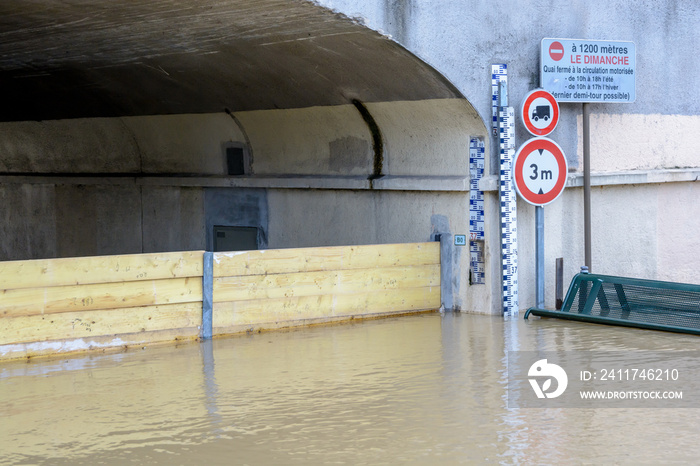 Flood markers and road signs at the entrance of a tunnel flooded by the important rise in the water level of the river Marne.