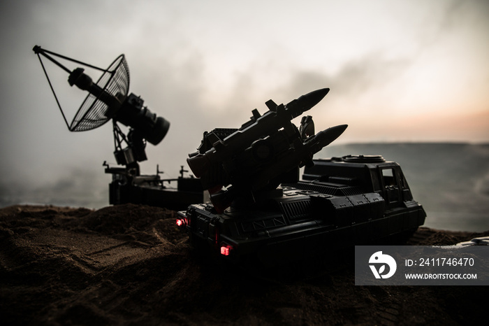 Creative artwork decoration. Silhouette of mobile air defence truck with radar antenna during sunset. Satellite dishes or radio antennas against evening sky.