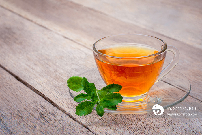 Glass cup of herbal tea with stevia leaf isolated on wood table background.