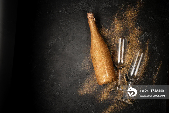 Romantic photo of golden champagne bottle, two wine glasses on black stone background